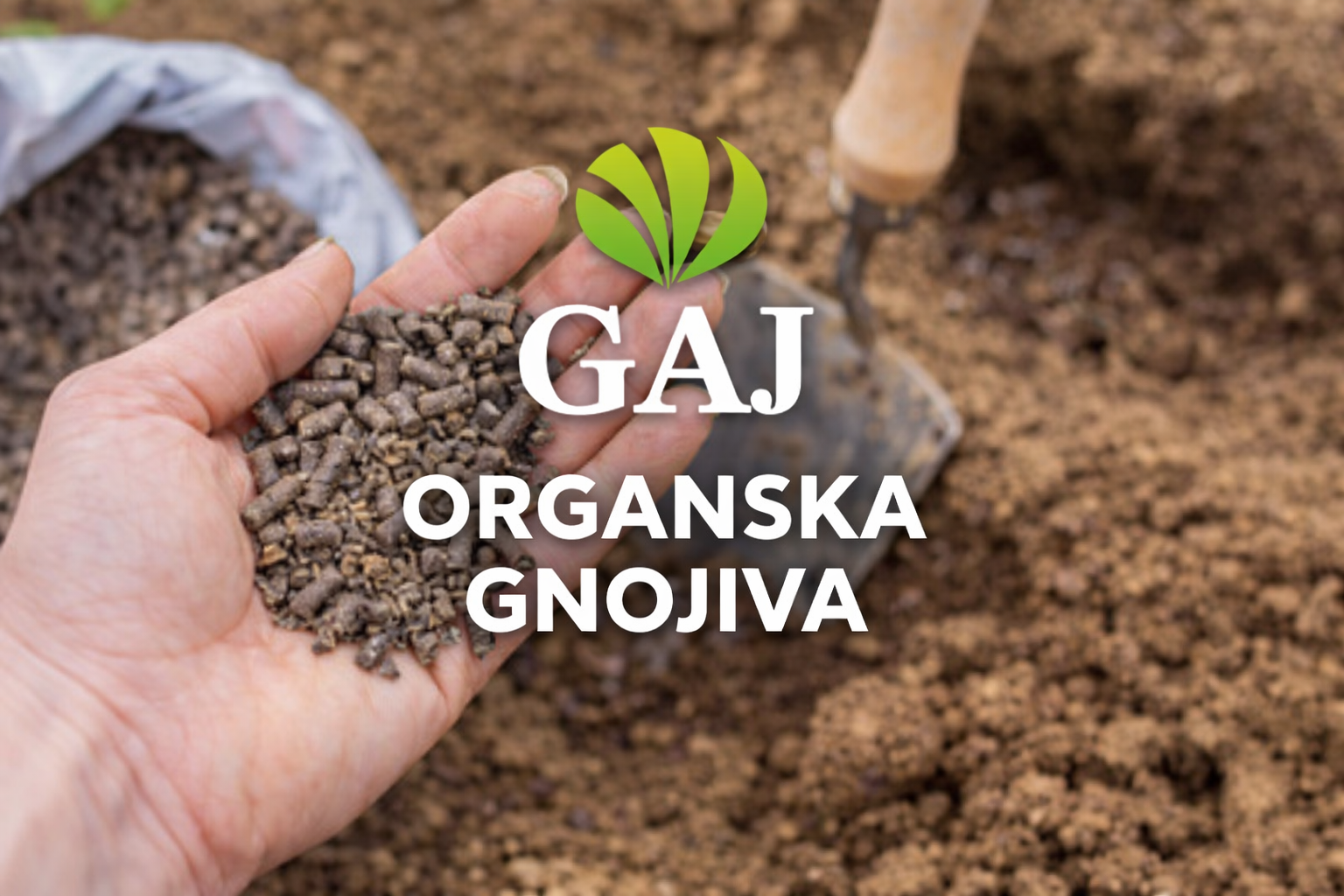 Organsko gnojivo u granulama u ruci iznad obrađenog tla – GAJ organska gnojiva
